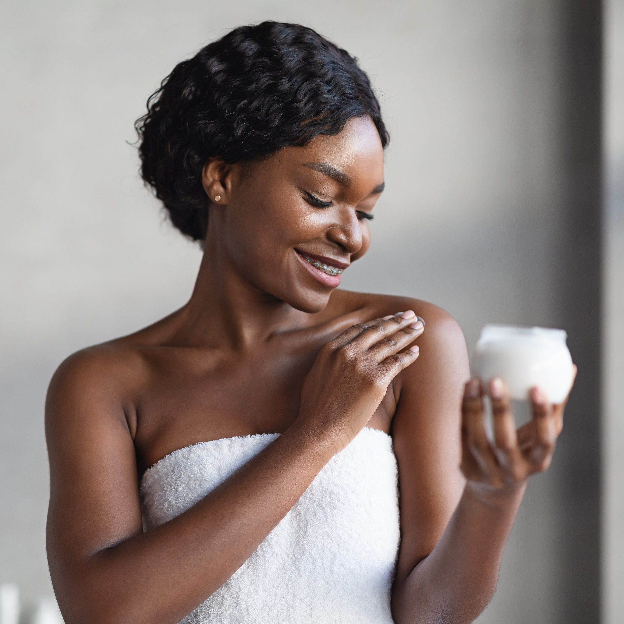 woman rubbing lotion on shoulder