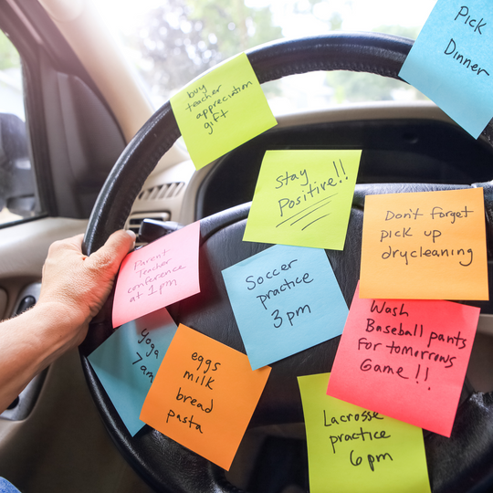 Image: Woman's hands on a steering wheel covered in sticky notes for tasks – a visual representation of managing tasks with ADHD, showcasing organizational challenges on the go.
