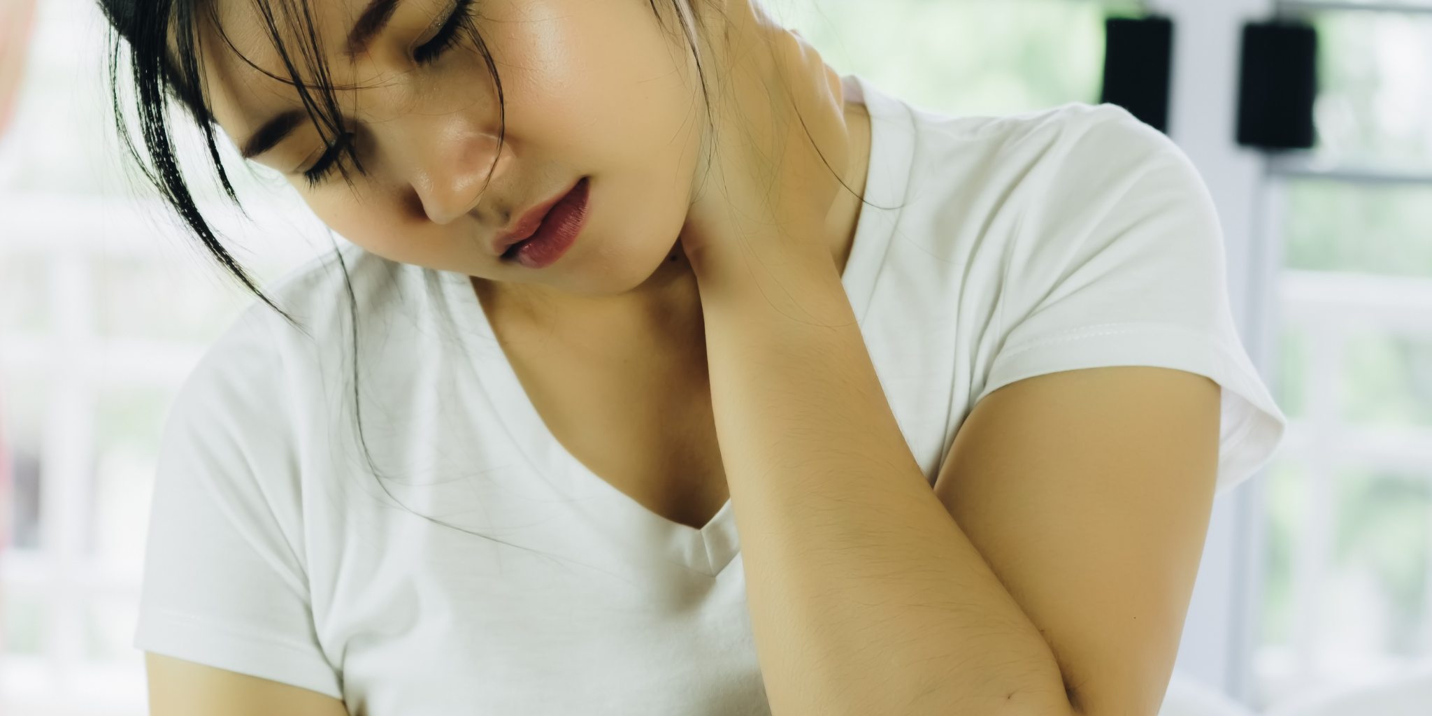 asian woman in white t-shirt rubbing neck