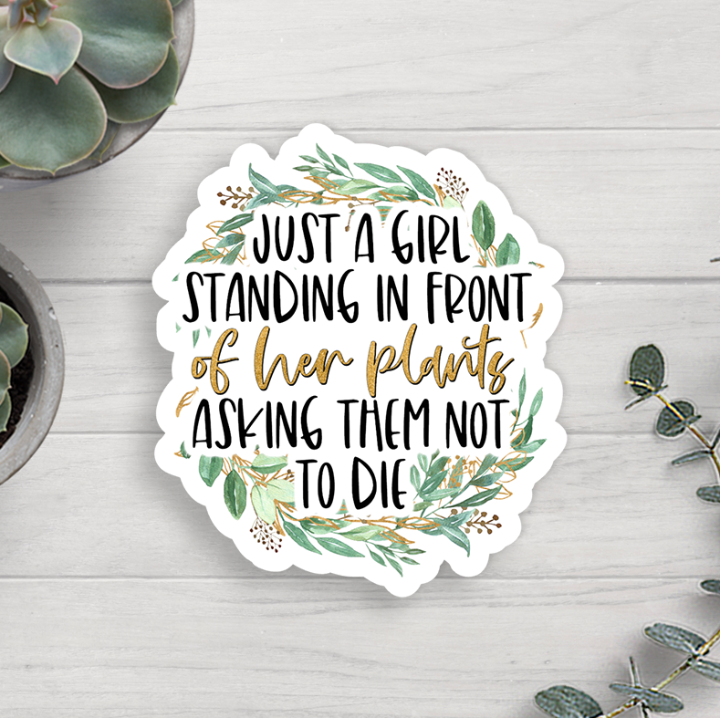 Sticker with text 'Just a girl standing in front of her plants asking them not to die' on a wooden surface with plants.