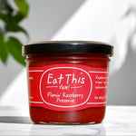 Jar of Flamin' Raspberry Preserve with a red label on a white surface.