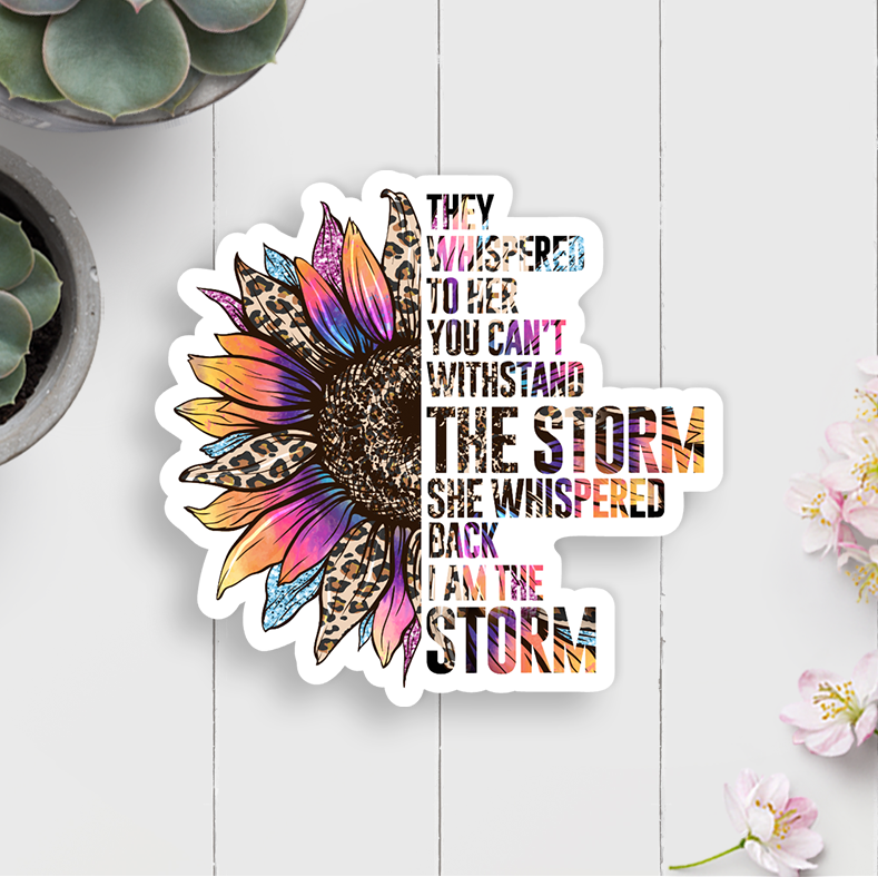 Colorful sunflower-themed sticker with motivational quote on a white wooden surface with plants.