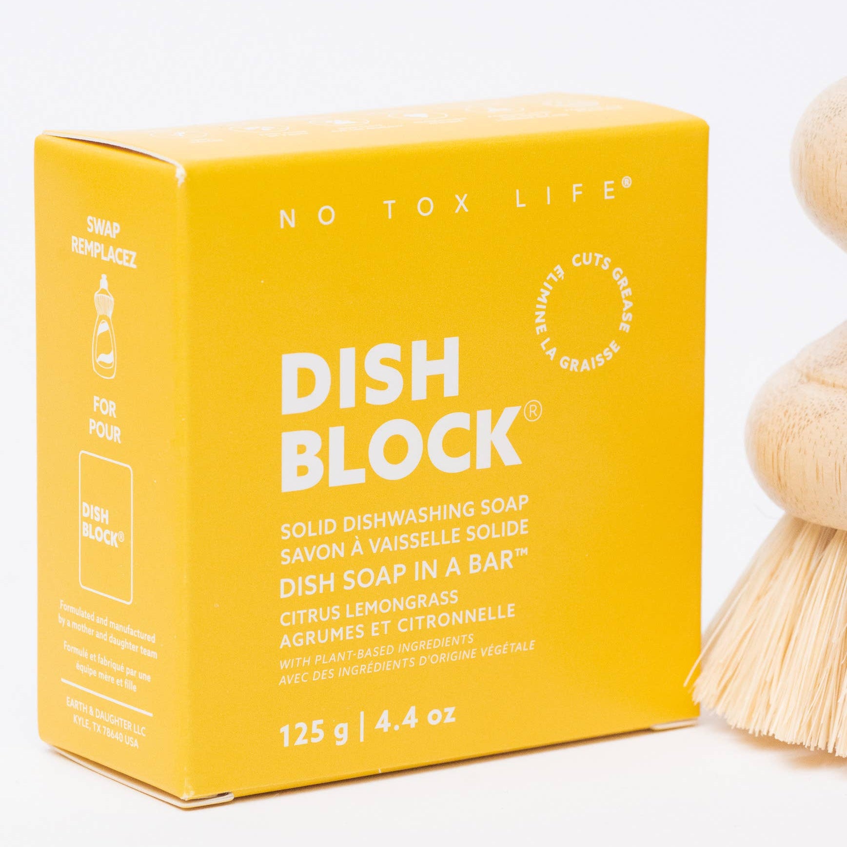 Yellow box of Dish Block solid dishwashing soap with a wooden dish brush on a white background