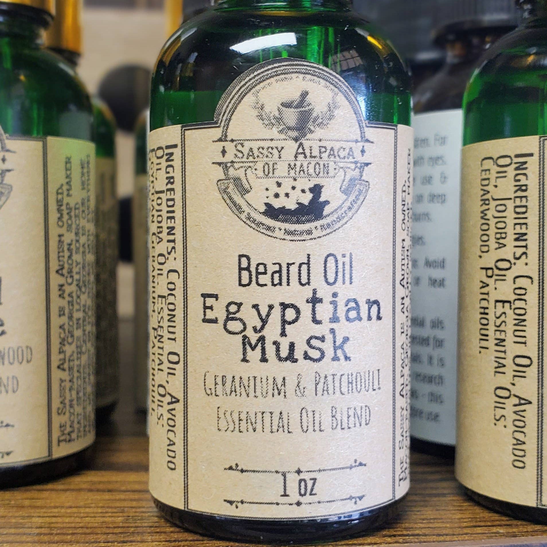 Green bottle of Egyptian Musk beard oil with dropper on a wooden surface.