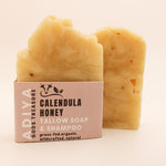 Two bars of 'calendula honey' tallow soap with a cardboard box on a beige background