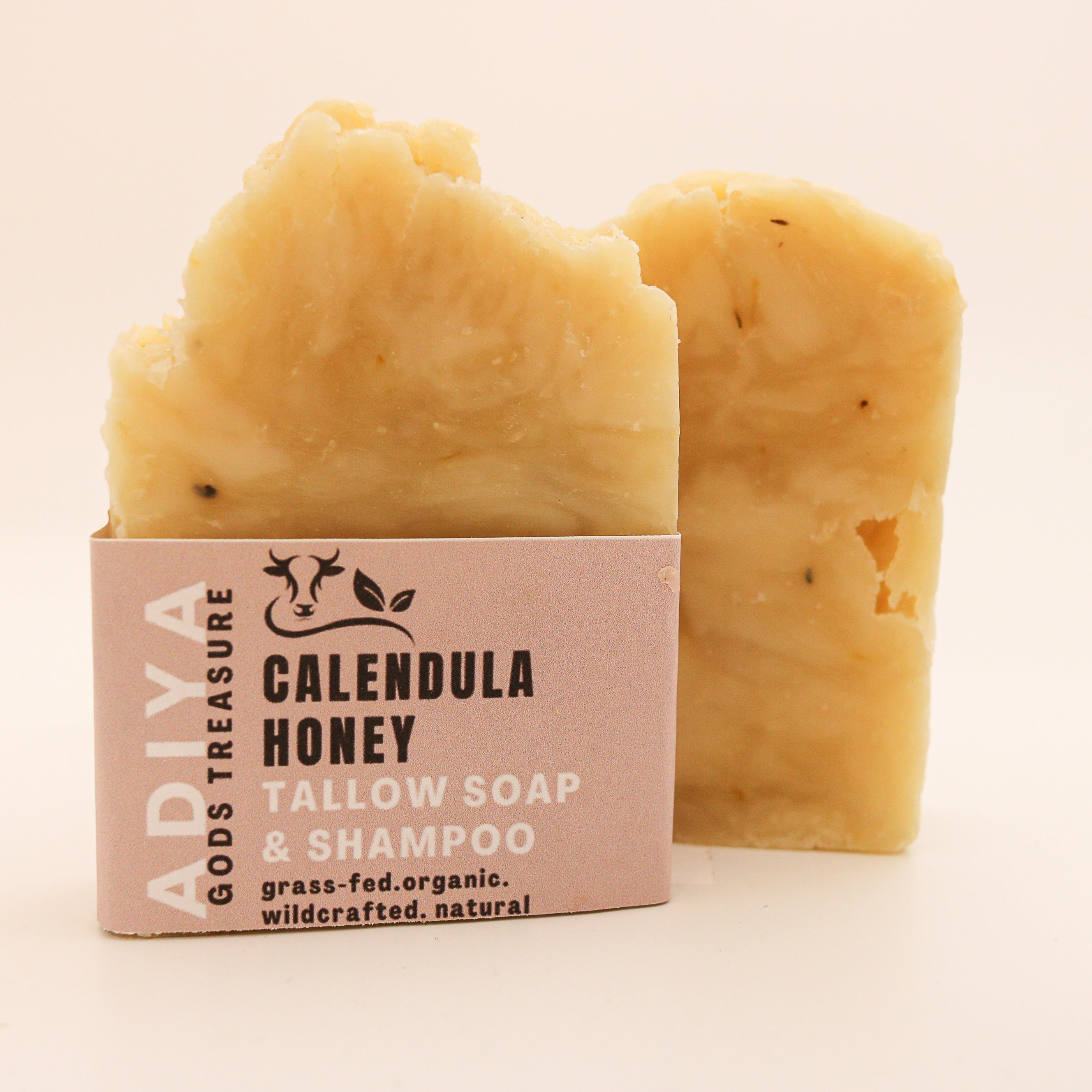 Two bars of 'calendula honey' tallow soap with a cardboard box on a beige background