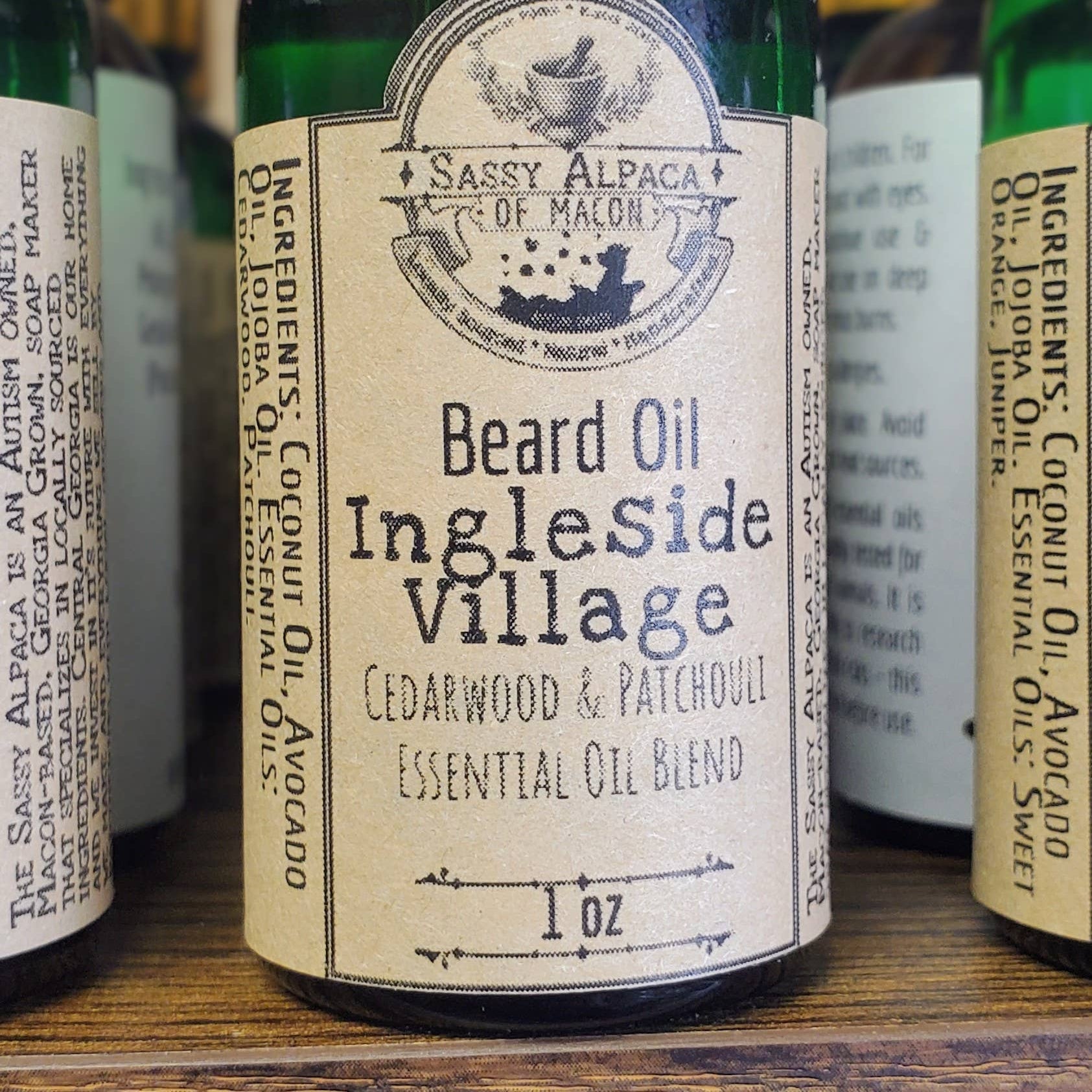 Bottle of Sassy Alpaca of Malton Beard Oil with a gold cap and label on a wooden surface.