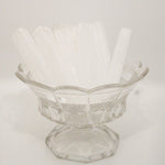 Clear glass footed bowl on a white background with selenite crystal wands in it