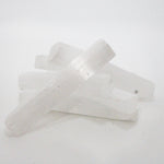 stack of selenite crystal wands on white background