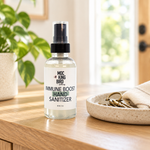 Mockingbird Apothecary Immune Boost Hand Sanitizer on a wooden entryway table beside a ceramic key tray, cream cloth and leafy plant.
