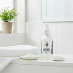 Unscented Magnesium Oil Spray – on bathroom shelf with white washcloth, magnesium flakes and potted plant on window sill