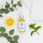 Eucalyptus & Jojoba Rejuvenate Massage Oil flat lay on white surface with eucalyptus sprigs, lemon and peppermint