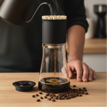 Fellow Stagg XF Tall pour over set mid-pour with gooseneck kettle, coffee dripping into tall glass carafe on wood surface