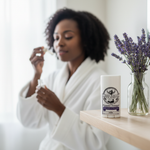 Lavender & Tea Tree deodorant on bathroom shelf with Black woman doing morning skincare routine in background