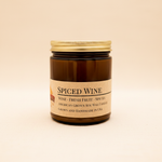 Spiced Wine soy candle in amber apothecary jar on warm cream linen background with shadow
