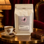 Vienna’s Blend coffee on a brass table with a porcelain coffee cup and book against burgundy velvet