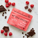 Mocca Shot High Energy Gummies – Dark Chocolate Raspberry lifestyle flat lay with raspberries, dark chocolate shards, and coffee beans on white marble