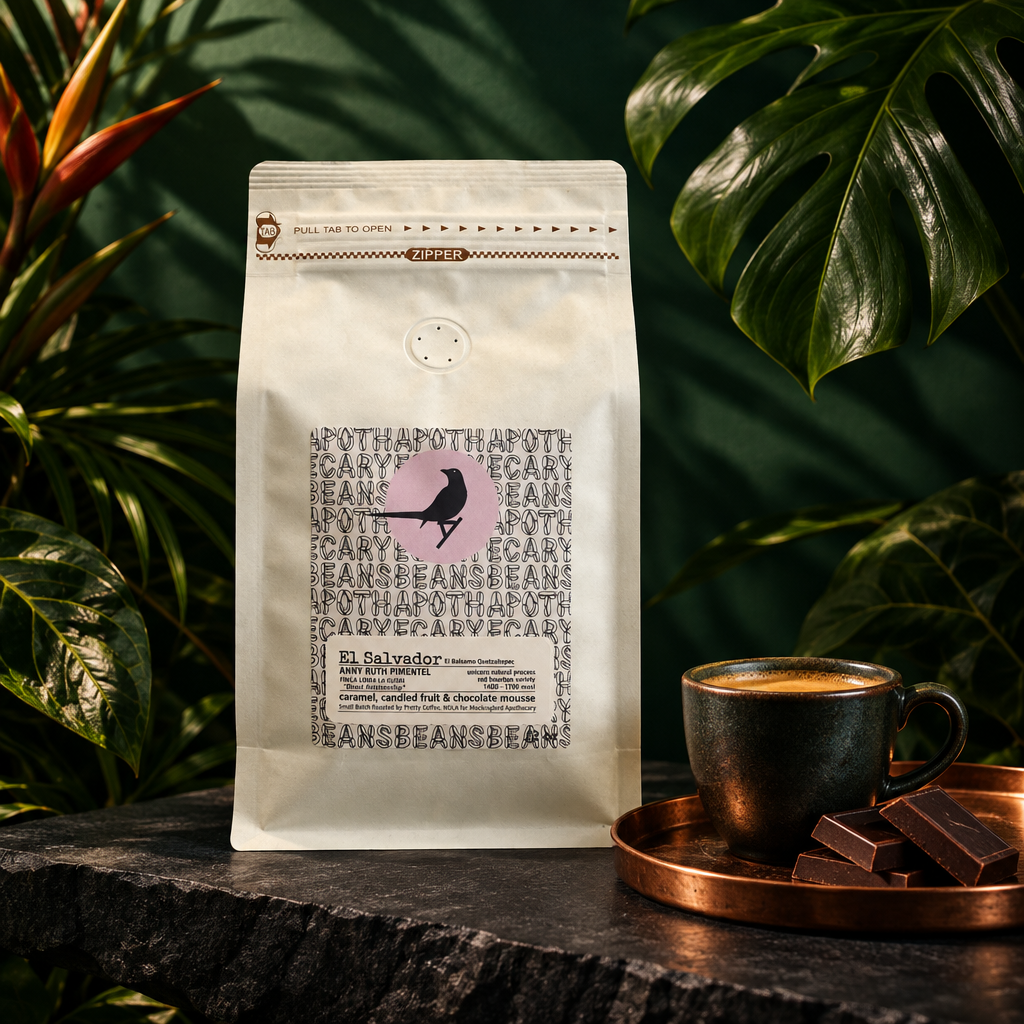 El Salvador coffee bag on dark slate with tropical leaves, a copper tray and espresso cup