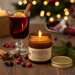 Spiced Wine candle lit on festive holiday table with mulled wine glass, orange slices, cranberries and pine