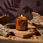 Frankincense amber candle with a black lid in a terracotta, bark and golden resin still life