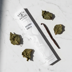Patchouli Vanilla incense lifestyle flat lay with dried patchouli leaves and vanilla bean on white marble