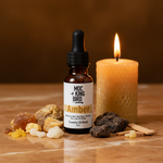 Amber Essential Oil Blend – eclectic on amber marble with raw amber resin, benzoin, labdanum, frankincense and beeswax candle