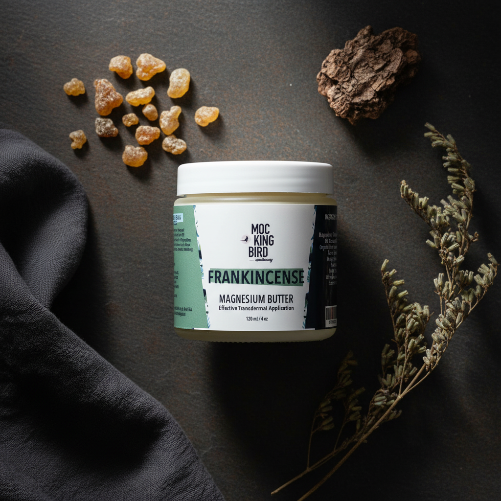 Frankincense Magnesium Butter flat lay on dark slate with frankincense resin tears and dried botanicals
