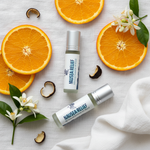 Nausea Relief rollerball flat lay with orange slices, neroli sprig and white linen