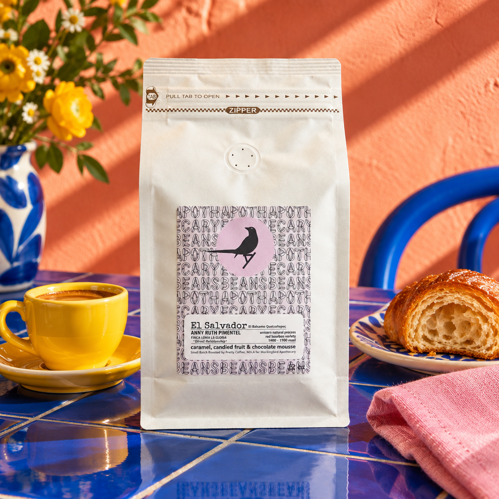 El Salvador coffee bag on a cobalt blue tiled breakfast table with a yellow cup and coral backdrop