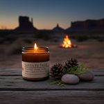Santa Fe Trail candle lit at desert dusk with piñon pine cones, cedar branch and desert stones