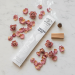 Sandalwood and Rose incense lifestyle flat lay with dried rose petals and raw sandalwood on white marble