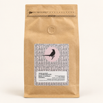 Phase Blend coffee in a kraft pouch with bird label on a pale studio background
