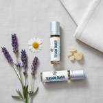 Tension Tamer rollerball flat lay with lavender sprigs, chamomile, frankincense resin on soft linen