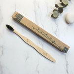 Bamboo charcoal toothbrush with kraft paper eco packaging flat lay on marble