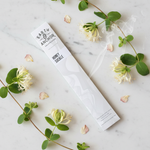 Honeysuckle incense lifestyle flat lay with fresh honeysuckle blossoms and petals on white marble