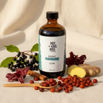 Mockingbird Apothecary Organic Elderberry Elixir styled with elderberries, hibiscus, ginger, rosehips, and cinnamon on cream linen