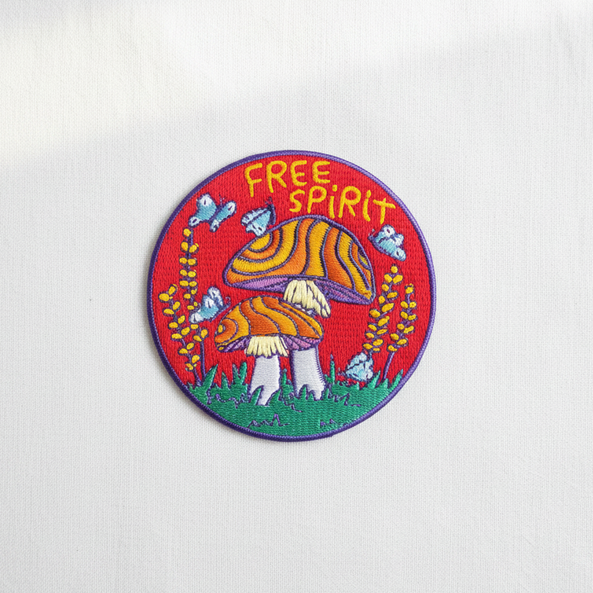 Free Spirit mushroom embroidered patch on clean white surface