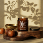 Mulled Cider amber candle on a walnut riser with apples and an antique brass bowl in golden autumn light