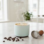 Fellow Monty double wall ceramic cappuccino cup with latte art rosette on marble surface with coffee beans
