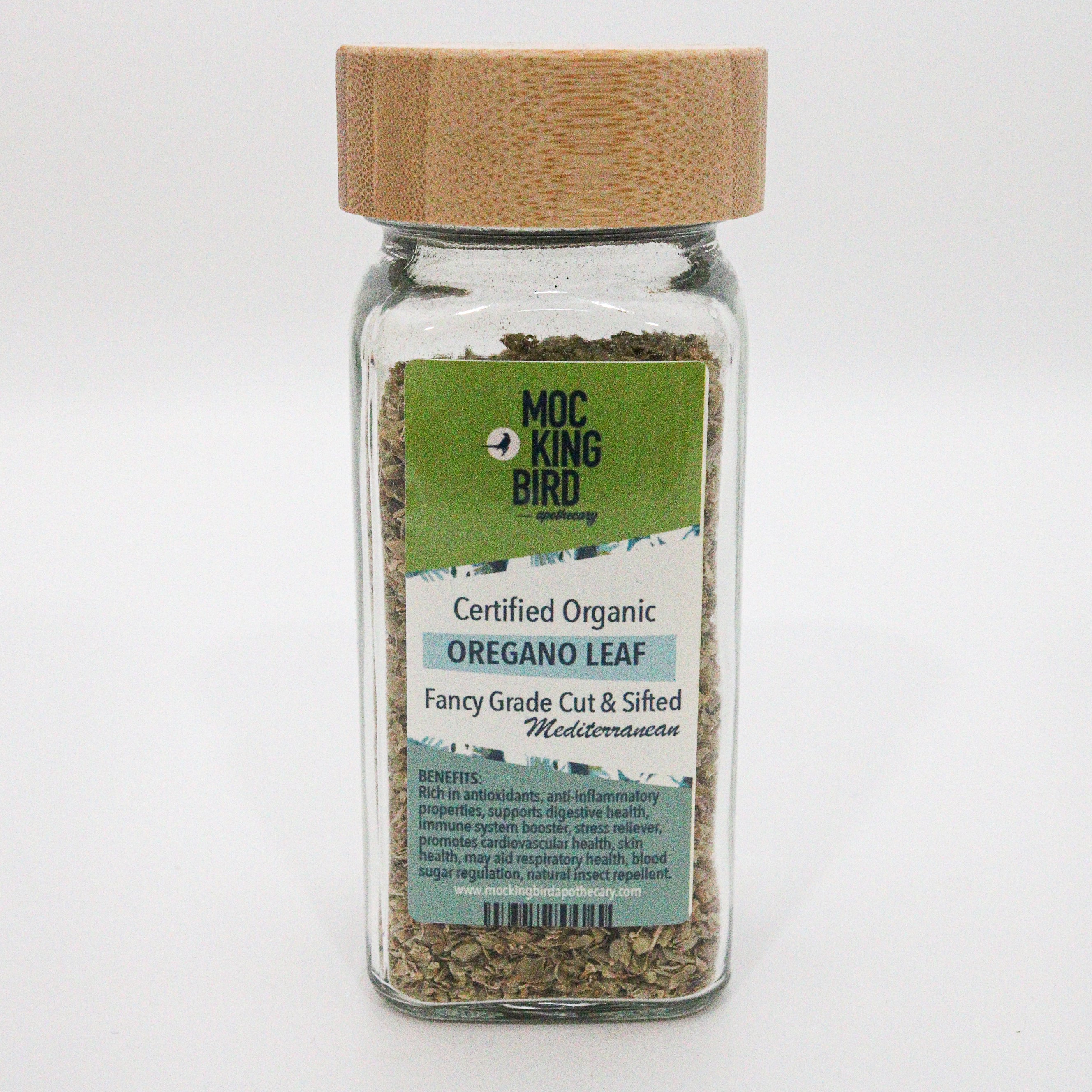 Glass jar of oregano leaf with a bamboo wooden lid on a white background