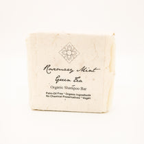 rosemary mint green tea shampoo bar wrapped in seed paper on white background