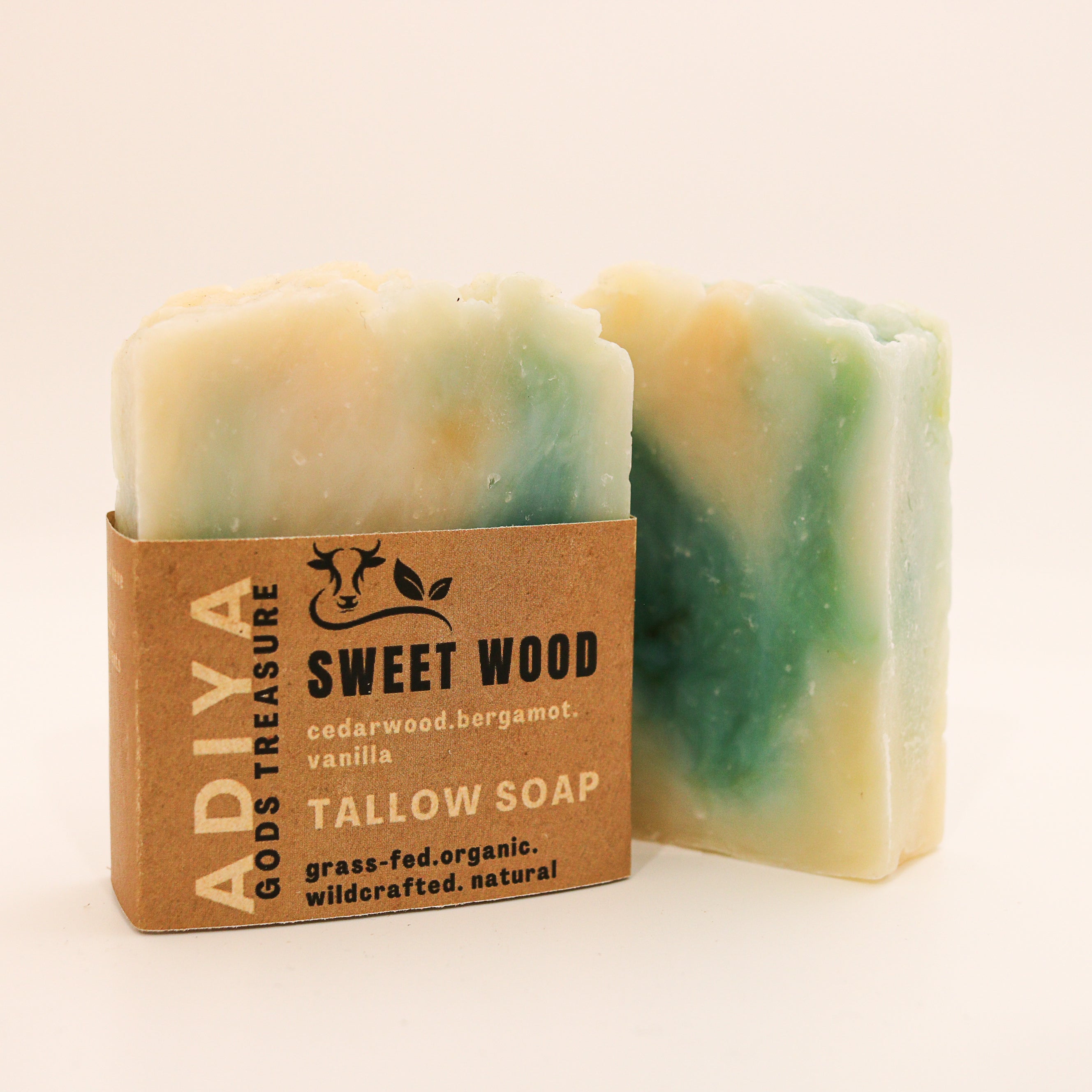 Two bars of tallow soap labeled 'sweet wood' with a cardboard packaging label on a beige background