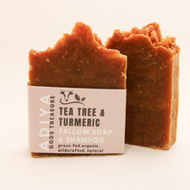 Two bars of soap with a 'tea tree & turmeric' label on a light background
